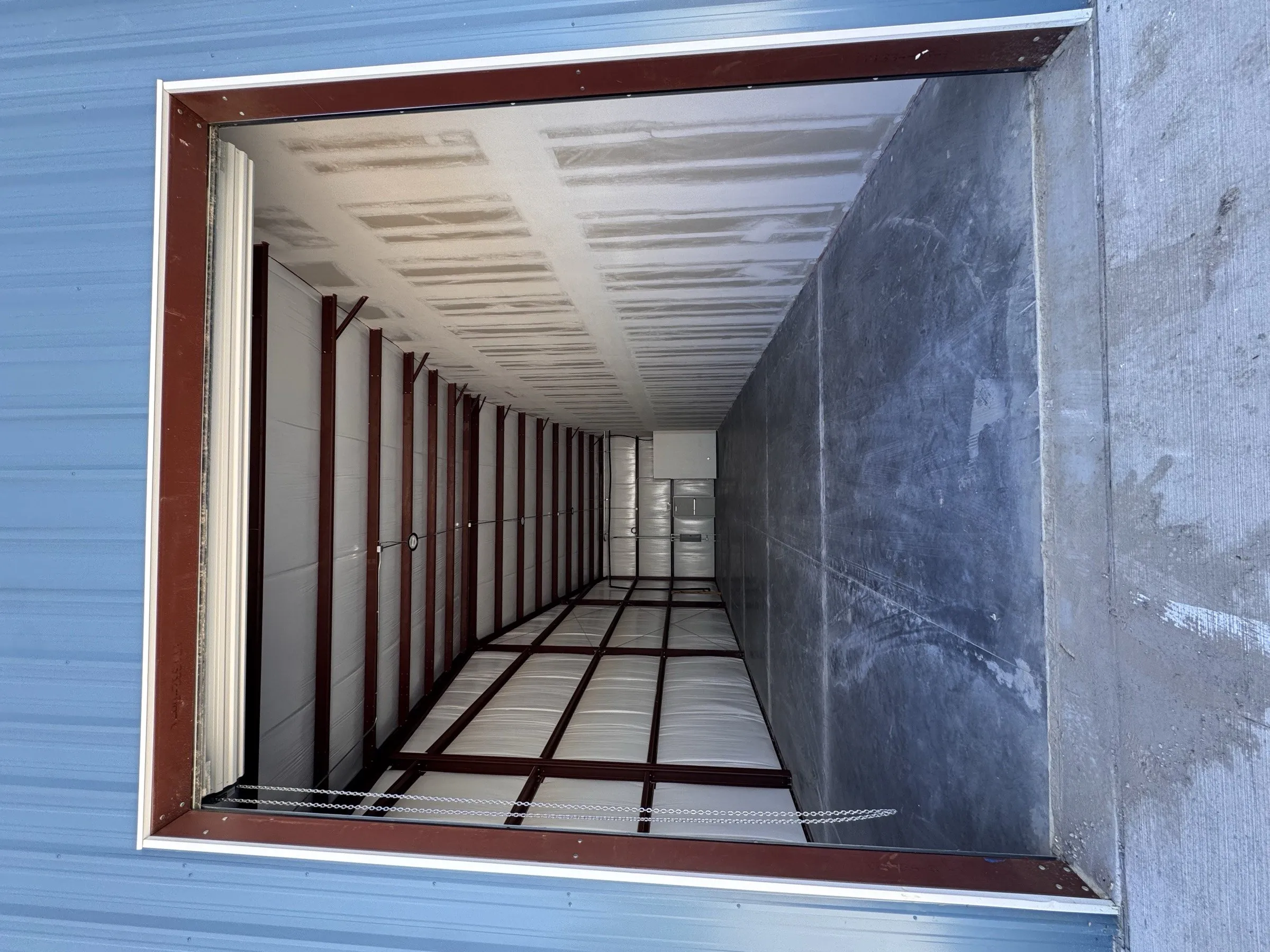 Looking into a bay through its open 12 by 14 foot roll-up door from the concrete apron outside.