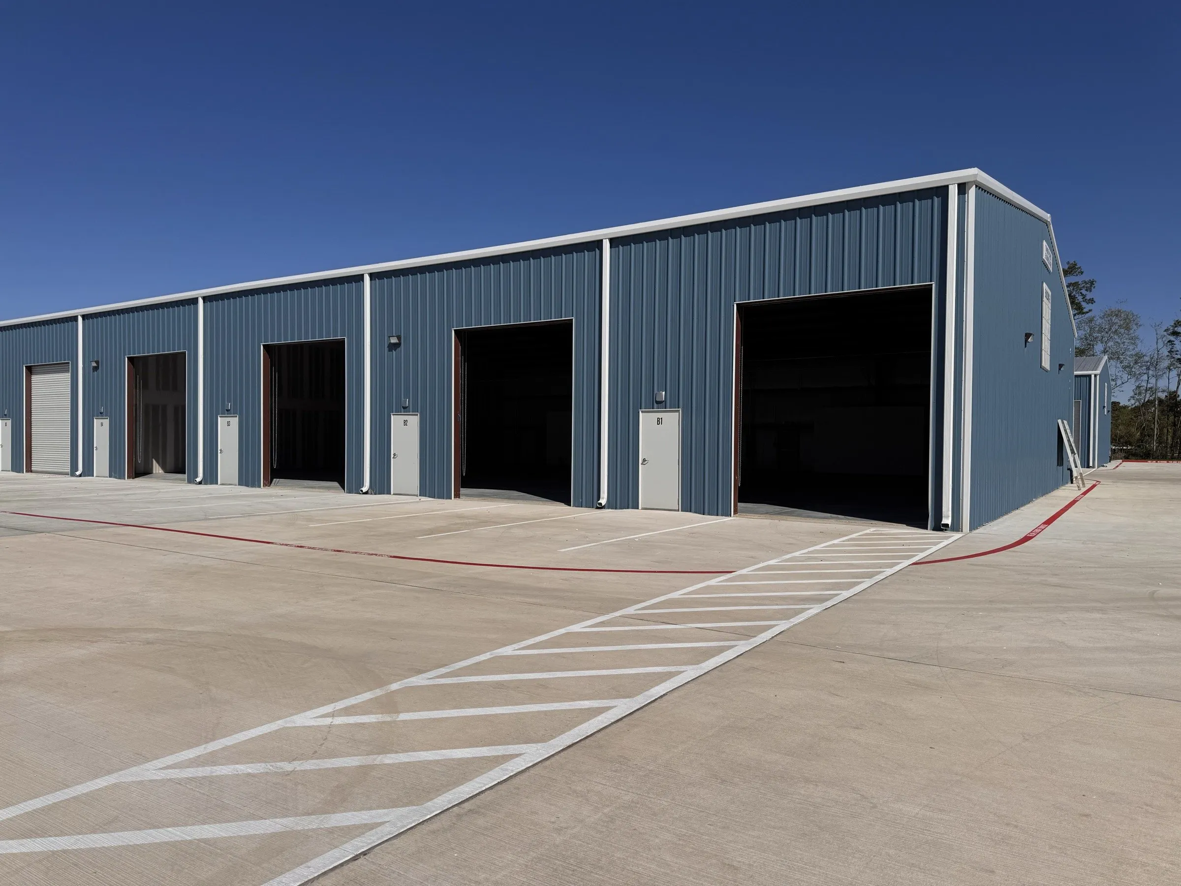 One of the buildings seen at an angle down its length, roll-up doors and man doors alternating.