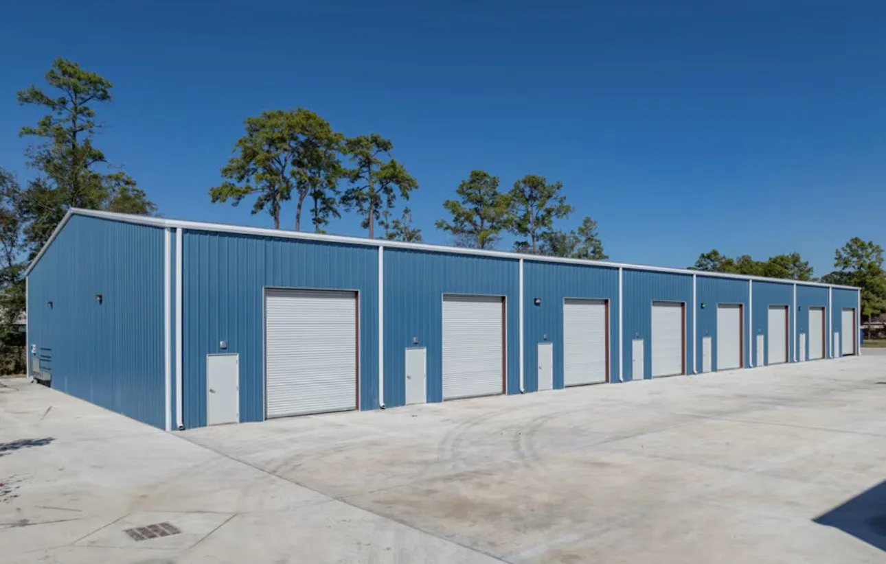 The long elevation of a building, all eight roll-up doors in a row under a blue metal wall.