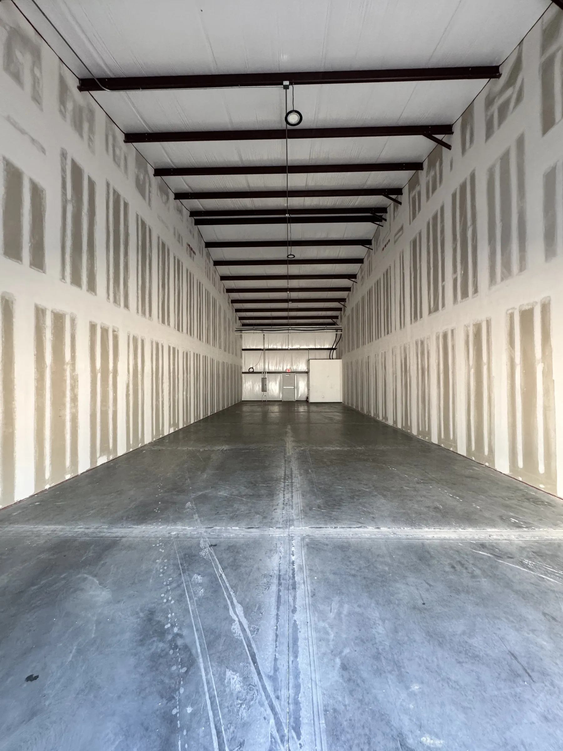 The full 80-foot depth of a single bay, exposed steel frame overhead.