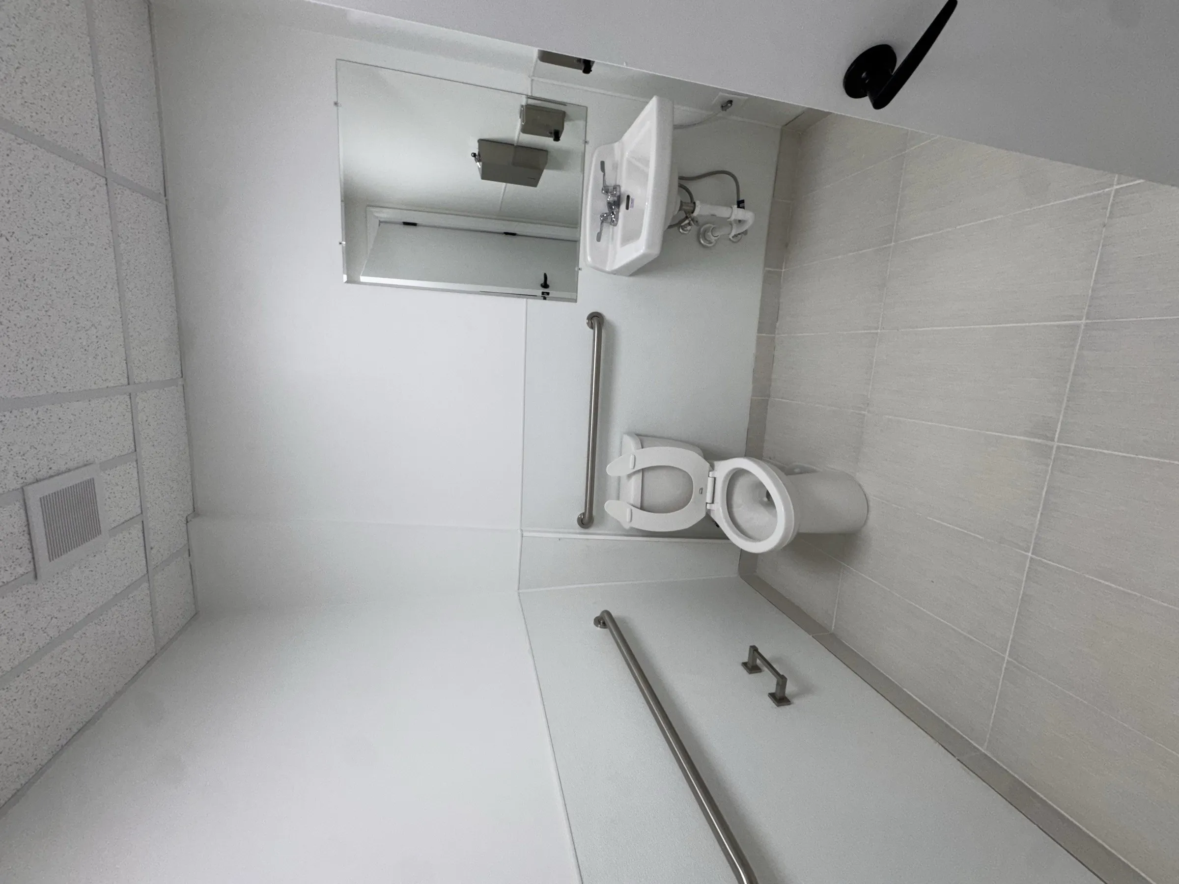 The private restroom inside a bay: tiled floor, sink, toilet and grab rail.