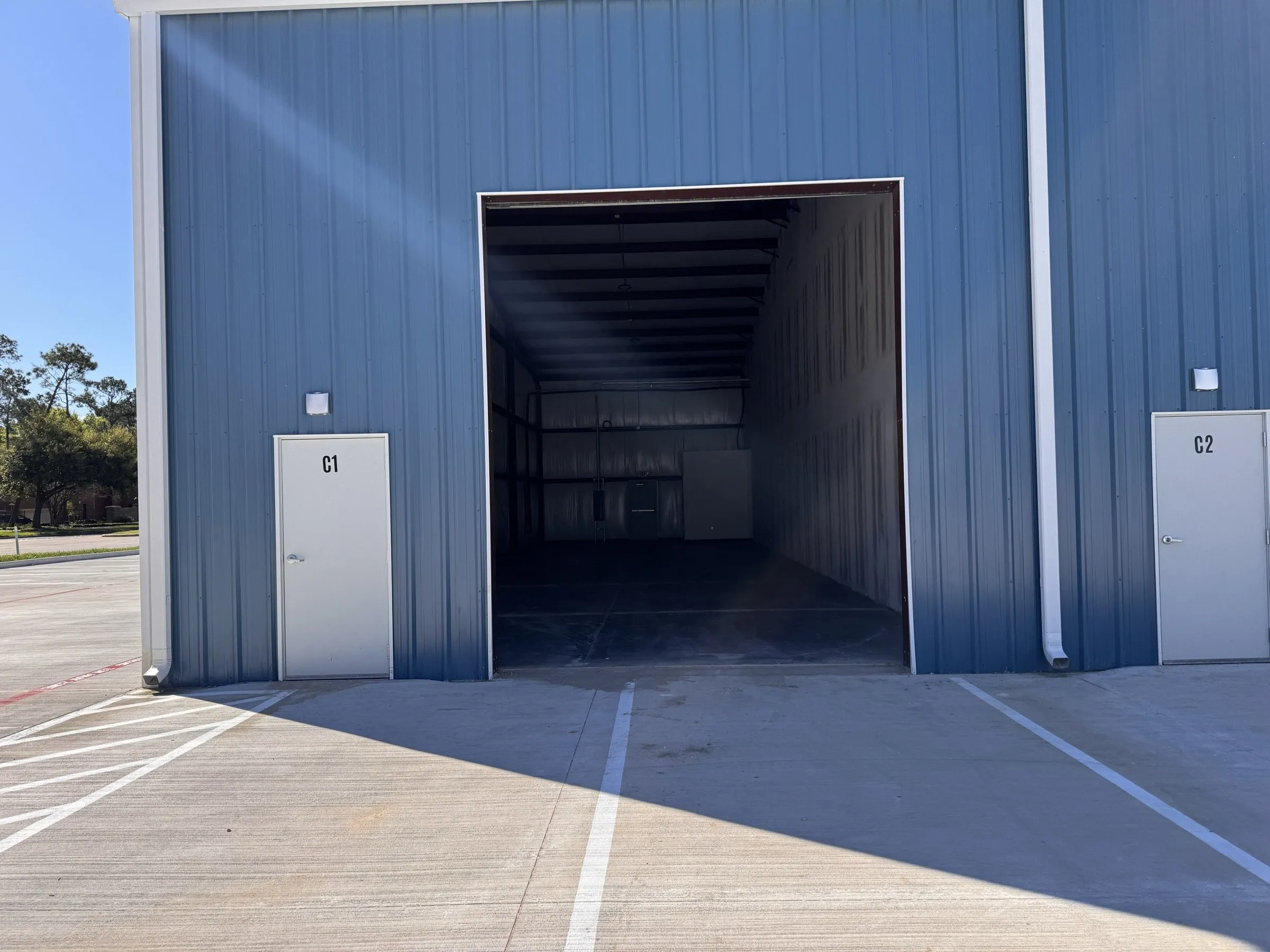 Unit doors C1 and C2 either side of an open roll-up door, with the bay interior visible beyond.